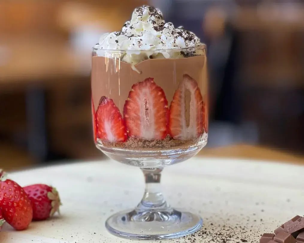Mousse Cup Topped With Whipped Cream And Strawberries