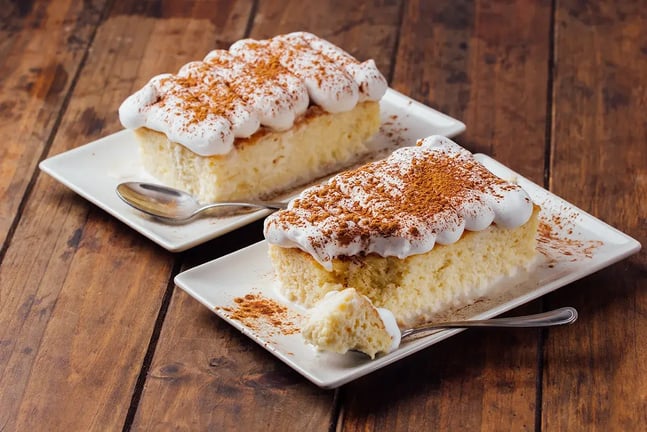 Feature Image - Tres Leches Cake with piped whipped cream garnish and cocoa powder dusting