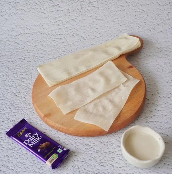 Crispy Rolls with Coconut and Dairy Milk Chocolate- Cut the samosa sheet in half
