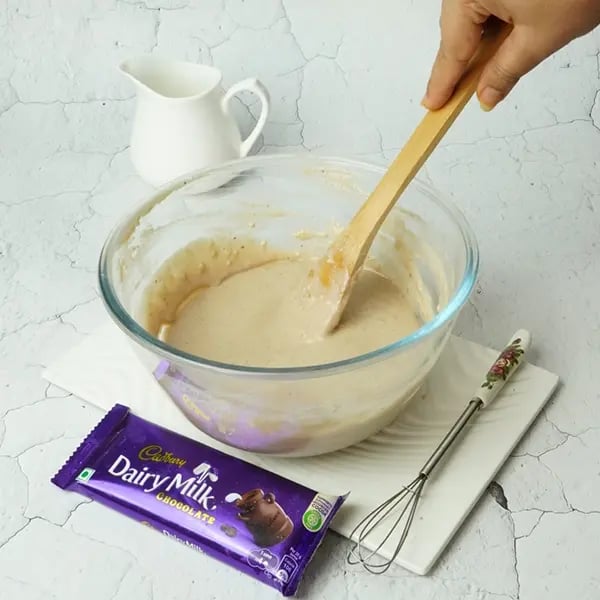 Dairy Milk Covered Cinnamon Loukoumades-Mix with a wooden spoon