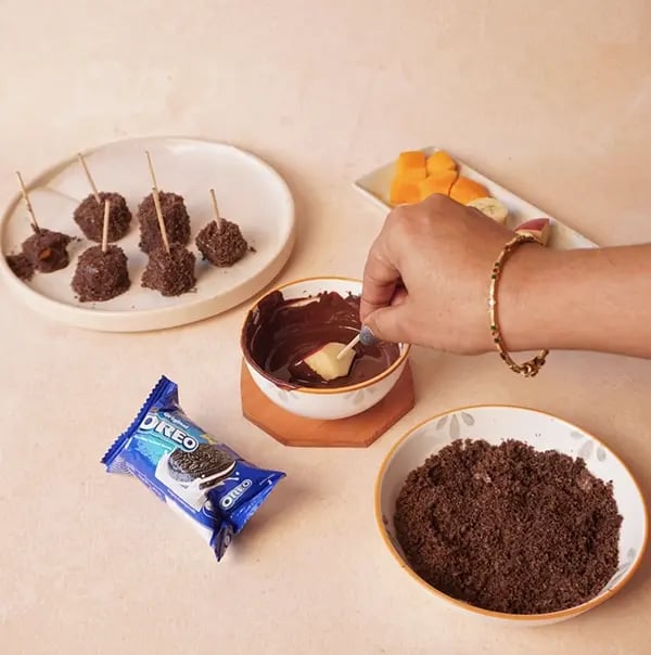 Frozen Bournville Chocolate Fruit Bites with Oreo Dust-Using a toothpick dip each piece of fruit